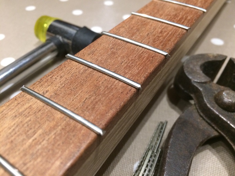 Hammering in the frets with a soft faced hammer.